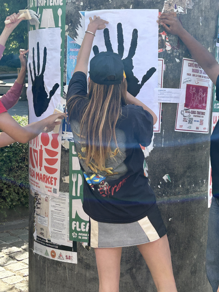 Action de collage d'affiches Basta représentant des mains noires dans l'espace public bruxellois