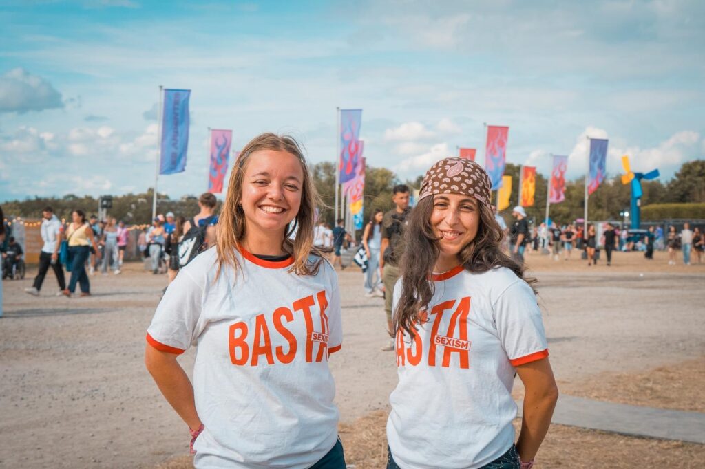 Deux bénévoles de l'association Basta souriantes portant le t-shirt "Basta Sexism" lors d'un festival