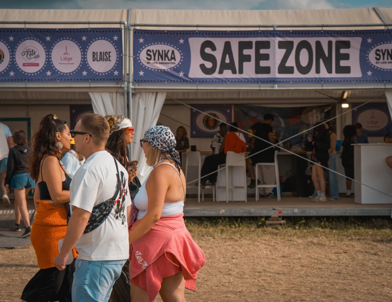 Festivaliers passant devant le stand Safe Zone en partenariat avec Basta lors d'un festival