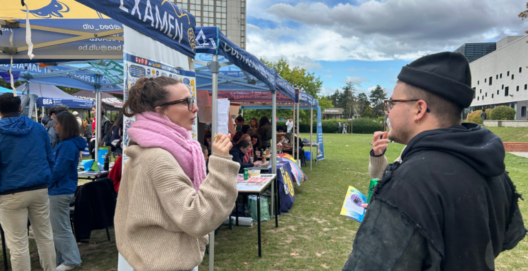 Stand de Basta sur un campus universitaire, échange avec un étudiant, affiche sur le sexisme dans l'espace public